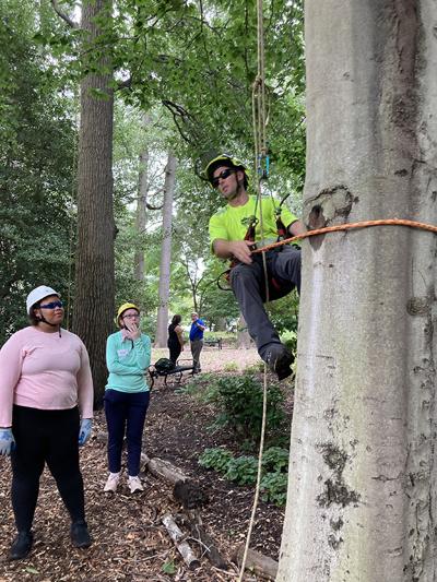 Rob Ash of Bartlett Tree Experts shows a double-rope tree climbing technique to Nevaeh Murphy, left, and Fiona Cox during the Urban Forestry Careers Camp. (Photo by Timothy B. Wheeler/Chesapeake Bay Journal)