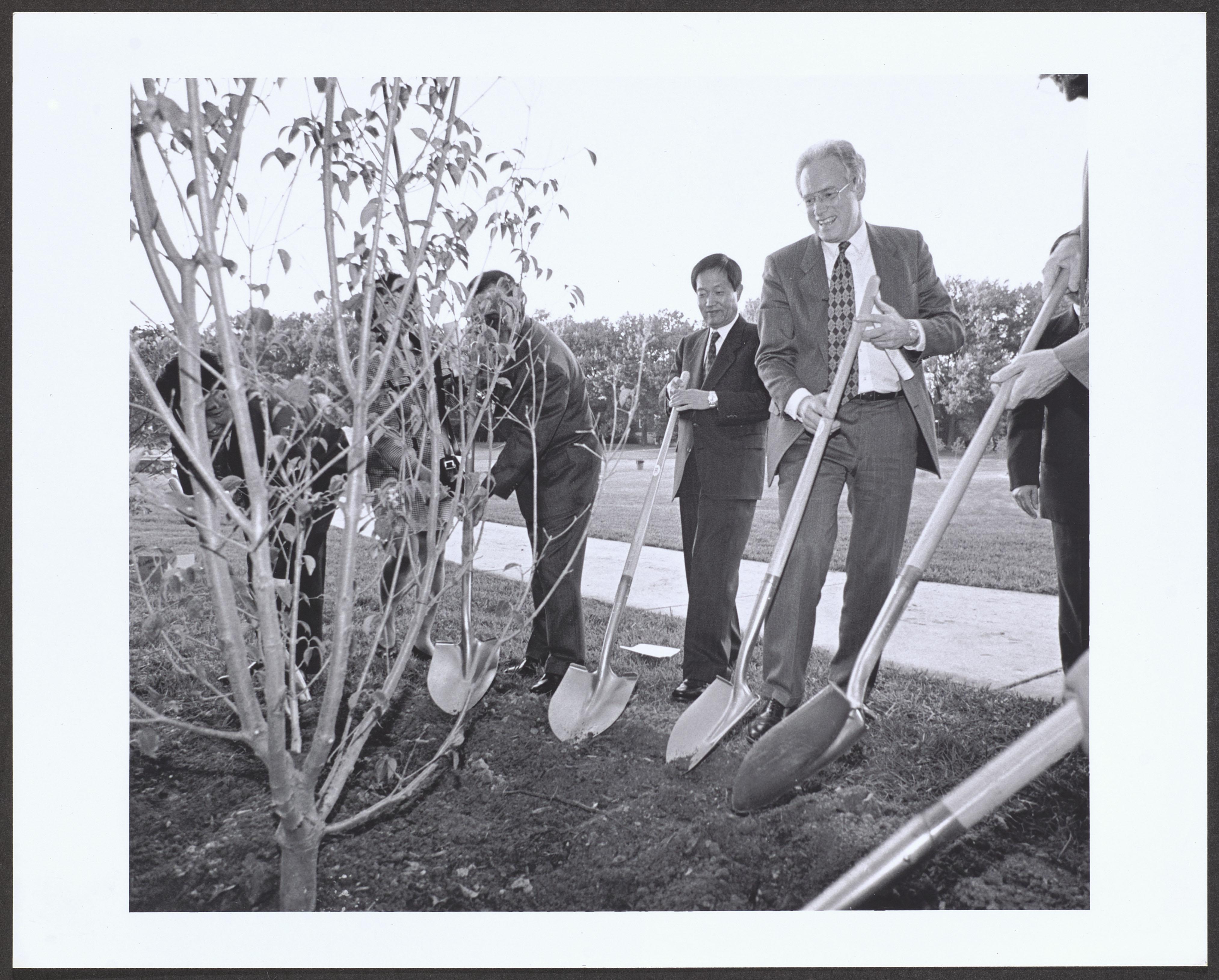 William _Brit_ Kirwan, University President, and six other people ceremoniously planting a tree, undated